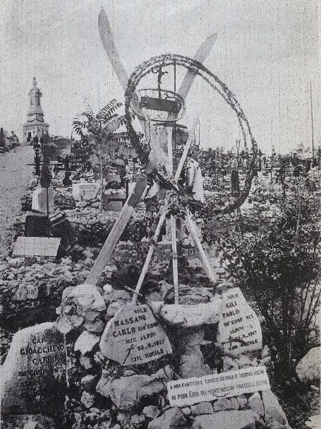 A stone memorial with wooden wheel and inscriptions amidst a cemetery.