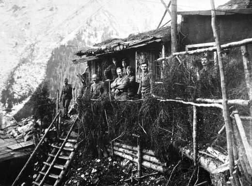 Black and white photograph of a wooden building with ladders, surrounded by rocky terrain.