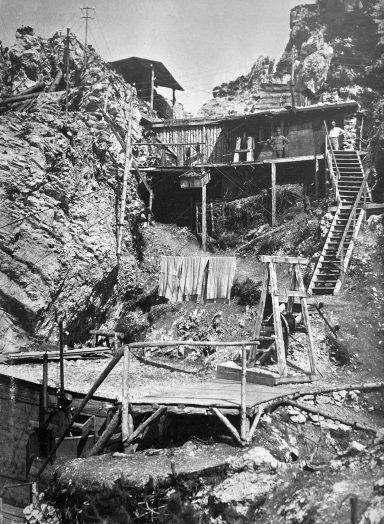 Abandoned wooden structures on rocky terrain with ladders and a platform.