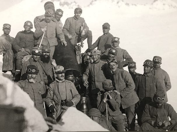 Group of soldiers posed on snowy terrain, wearing military uniforms and gear.