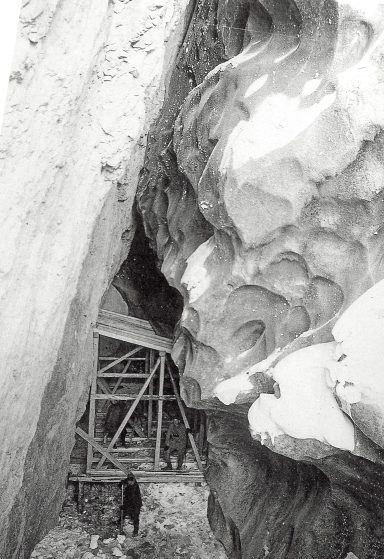 A rocky landscape with a wooden structure near a cave entrance.