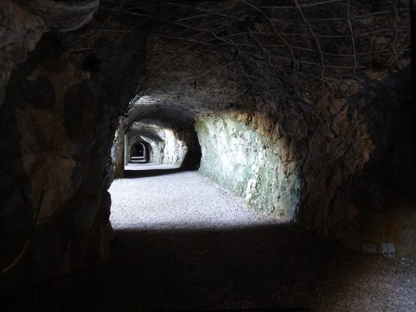 Dimly lit pathways inside a rocky cave, with natural light illuminating the walls.