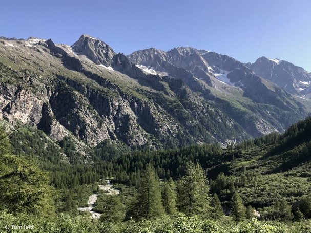Scenic mountain landscape with lush valleys and rocky peaks under a clear blue sky.
