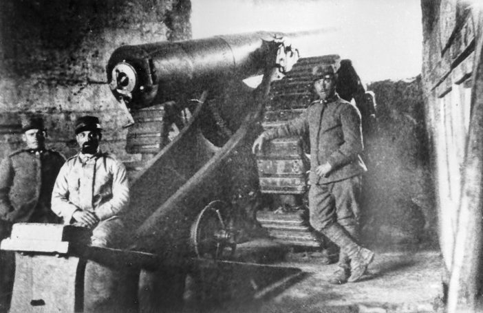 Soldiers operating a large cannon in a military setting.