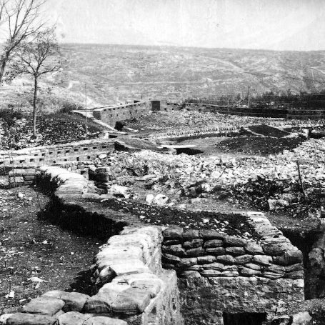 Historic landscape featuring stone ruins and a desolate terrain under a cloudy sky.