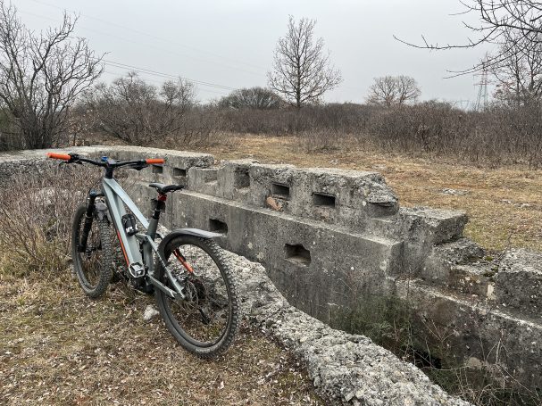 A mountain bike next to a weathered stone structure in a grassy landscape.