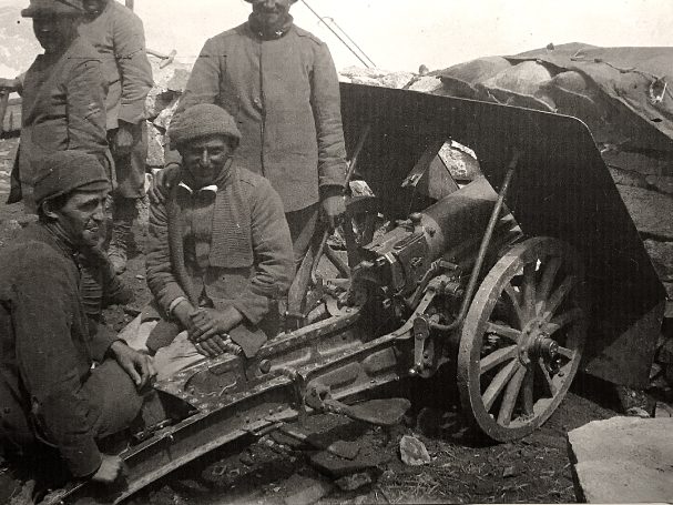 Soldiers gathered around a field artillery piece in a wartime setting.