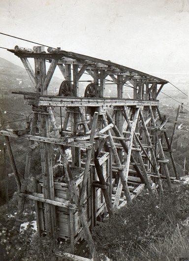 Old wooden structure with pulleys, set in a mountainous landscape.