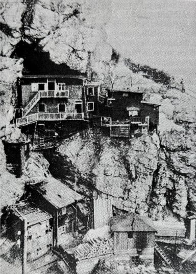 Cliffside houses built into rocky terrain, showcasing unique architecture and rugged landscape.